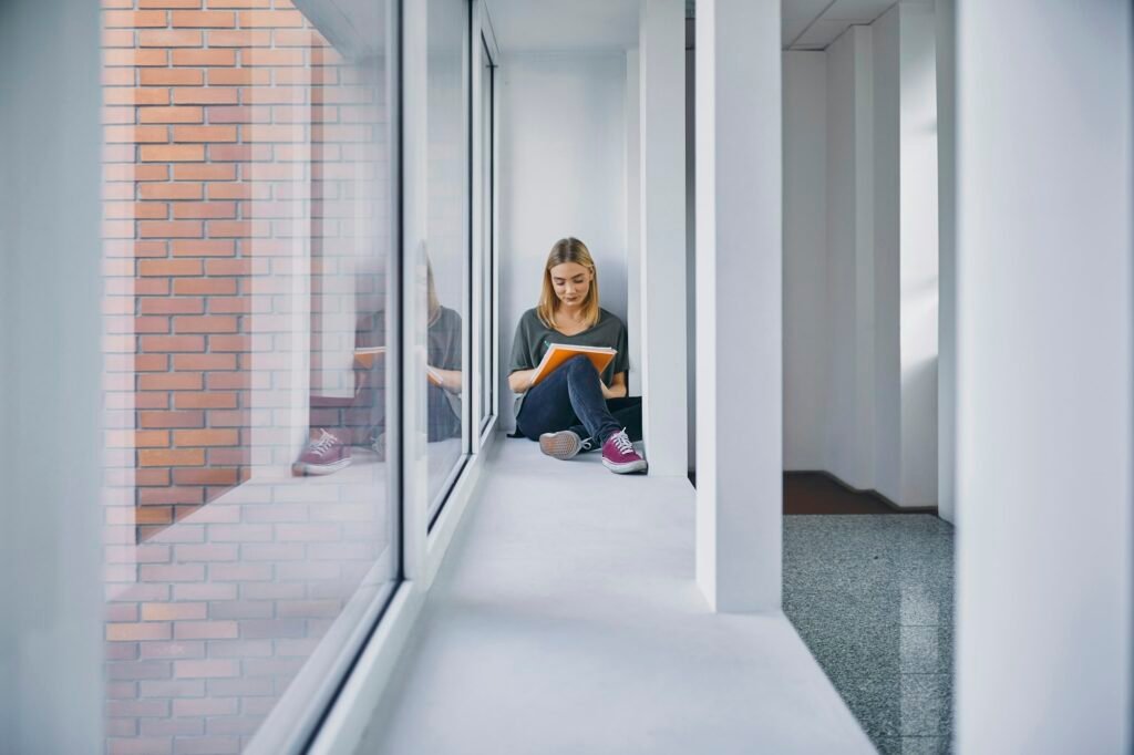 Student sitting at the window in hallway learning